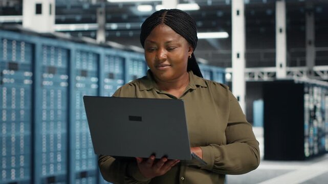 Programmer uses a laptop computer in a server farm for technology workflow management, supporting equipment monitoring, system reliability and server infrastructure management.