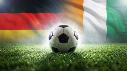 Fototapeta premium Football Fever: A classic soccer ball rests on a vibrant green pitch, framed by the national flags of Germany and Ivory Coast, evoking the excitement of international competition.