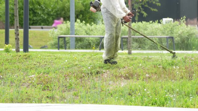 Industrial facility maintenance: A worker in a white coverall is tidying up the area using a gas-powered trimmer. The footage emphasizes the strictness of regulations at facilities with heightened hyg