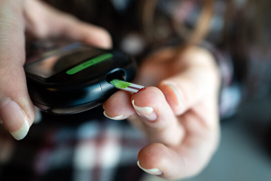 Hand inserting a test strip into a black blood glucose meter. Diabetes self-testing and home health technology. concept of health care in case of diabetes. Measuring blood sugar levels.