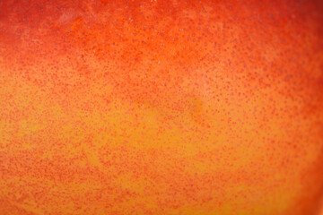 A detailed macro shot showing the speckled texture and vibrant orange and red colors of a fresh nectarine skin.
