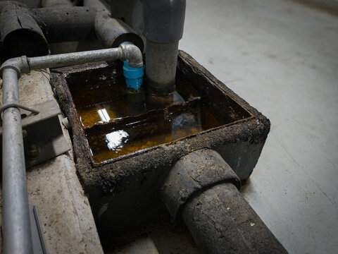 Close-up photo of industrial siphon drainage system with pipes and grease trap. Perfect for engineering, wastewater, and technical design themes.