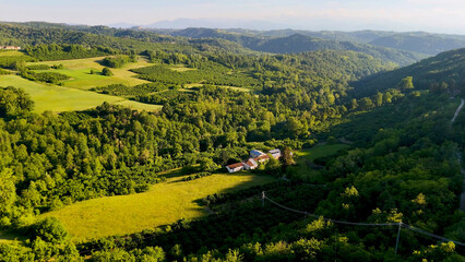 Fototapeta premium Aerial View of Lush Green Hills and Farmhouse in Piedmont Italy