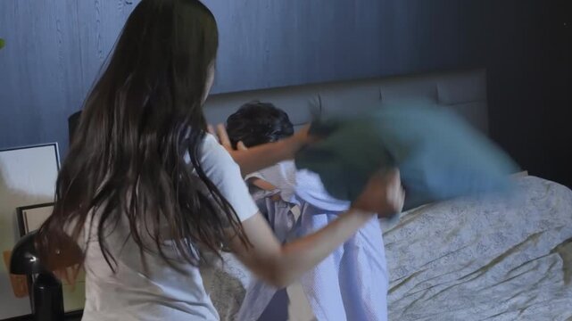Fighting couples battle of pillows, battered husband defends himself from being hit by abusive and violent wife, getting angry throwing tantrums, physical abuse, domestic violence, toxic relationship