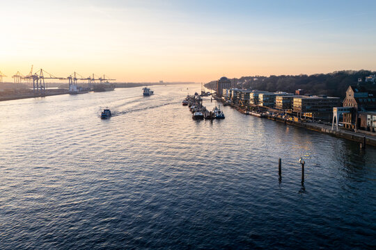 Aerial view of the Dockland building along the Elbe river with container ships, cranes, and calm water during the golden hour in Hamburg, Hamburg, Germany.
