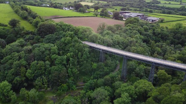 Meldon Viaduct stretches above thick woodland as the drone glides over surrounding Dartmoor farmland.