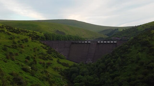 Meldon Dam cuts across a deep green valley on Dartmoor as the drone glides toward the massive concrete wall.