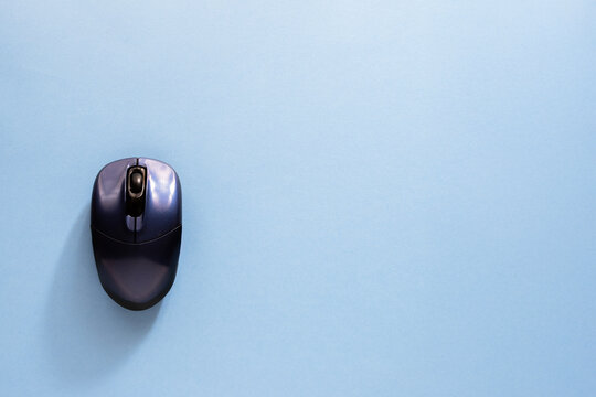 A computer mouse is placed on a solid light blue background with ample negative space. The image's simplicity and bright color make it perfect for technology, browsing, and online shopping themes.