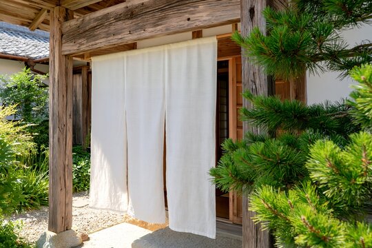 日本の伝統的な古民家の入口に白い暖簾がなびく情景
