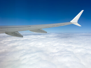Obraz premium Airplane wing soars above cloud cover