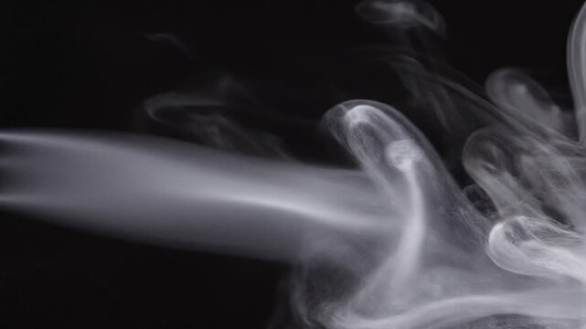 Cinematic slow motion white smoke plume flowing on black background.