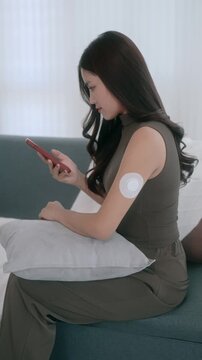 Asian woman using continuous glucose monitoring system at home