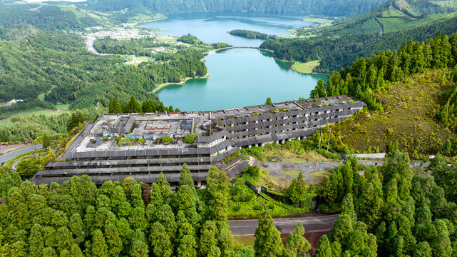 Aerial view of the abandoned Monte Palace Hotel nestled in lush green forests overlooking the twin lakes of Sete Cidades in Sete Cidades, Azores, Portugal.