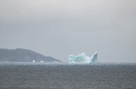 Iceberg drifts in the cold ocean on a grey day in Newfoundland