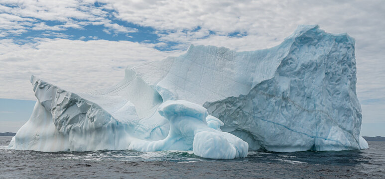 Giant sculpted iceberg floating in cold ocean water of Newfoundland