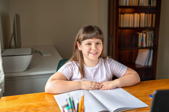 Smiling schoolgirl attending online lesson from home