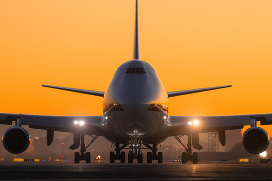 Large passenger jet taxiing on taxiway at sunrise