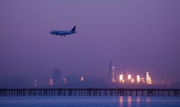 Airplane on final approach over a city at dusk