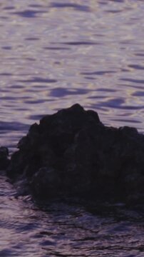 Sea weave around a single stone in water at dark 