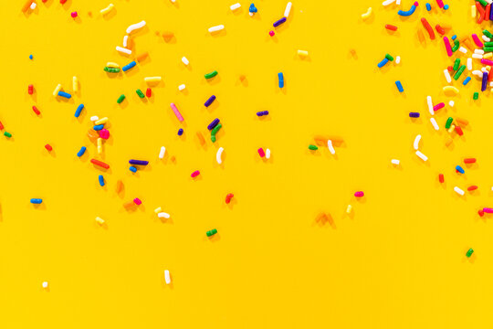 Evenly spaced sprinkles over yellow surface