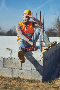 Construction worker having a heatstroke on a hot sunny day, headache, issues on a construction site outdoors.