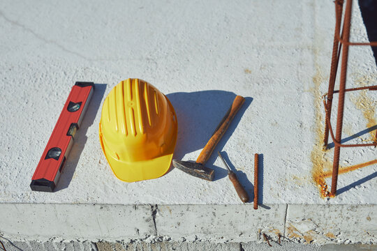 Construction tools and helmet on a cement foundation with iron rebar.