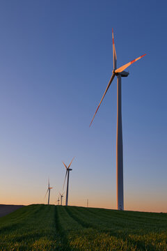 Wind turbines at sunset in green field &ndash; renewable energy, clean power, sustainable future.