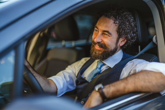 Smiling professional man driving car enjoying daily commute