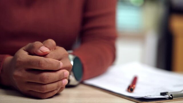 Close-up of a woman clasping her hands while sitting at a desk, expressing anxiety, uncertainty, and lack of confidence. Suitable for concepts of emotional stress, mental health, worry, and personal i