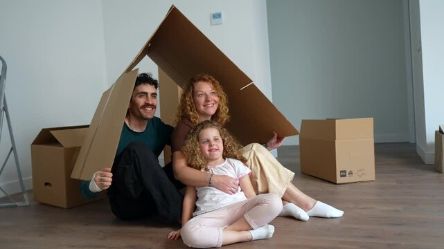 Happy family playing with cardboard boxes in their new home