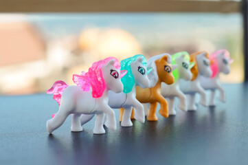 Small colorful unicorn figurines lined up on a dark tabletop. Playful toy collection concept for childhood imagination and creative learning © Наталья Красильников