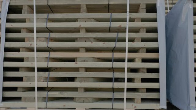 Large strapped stacks of wooden boards stored on pallets in an industrial warehouse