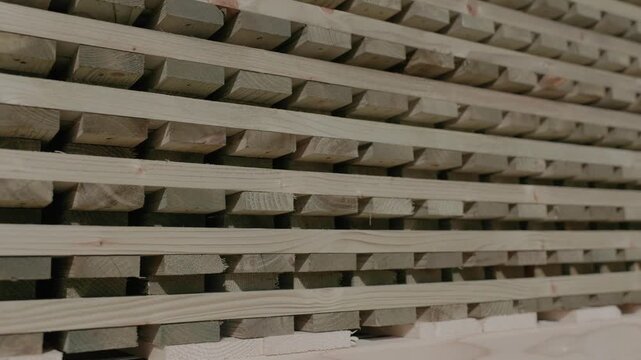 Close-up of stacked wooden boards with visible grain and spacers in a lumber workshop