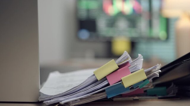 A close-up video of organized office documents with colorful index tabs stacked on a desk in a modern workplace. Ideal for illustrating business administration, document management, corporate workflow