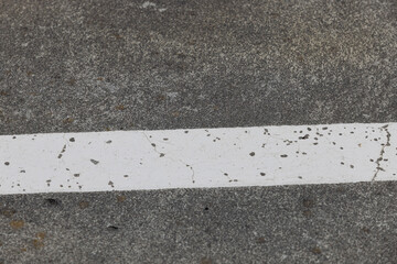 Fototapeta premium A faded white line runs diagonally across textured concrete, a minimal industrial floor detail.