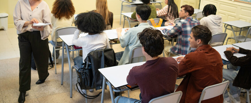 Teacher walking in a classroom with diverse students learning during a lesson