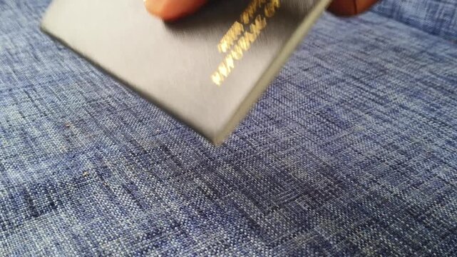 Closeup of international traveller hand pick up indian passport official personal identification document from table. Identity, citizenship, nationality, immigration or migration concept.