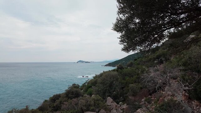 A beautiful cinematic shot of the rugged Sardinian coastline featuring lush Mediterranean brush and turquoise sea. This authentic nature scene captures the essence of sustainability and ecofriendly tr