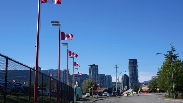 Row of Canadian Flags Waving in Urban Setting with Blue Sky and Mountains