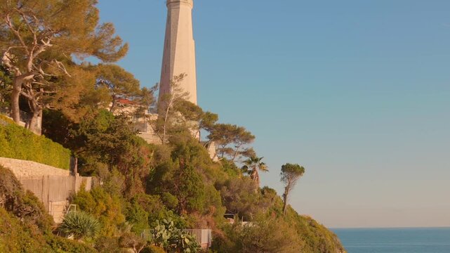 Tall lighthouse surrounded by tropical greenery scene on the Saint Jean Cap Ferra Island, France