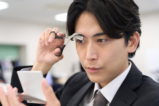 眉毛の手入れをするアジア人ビジネスマン