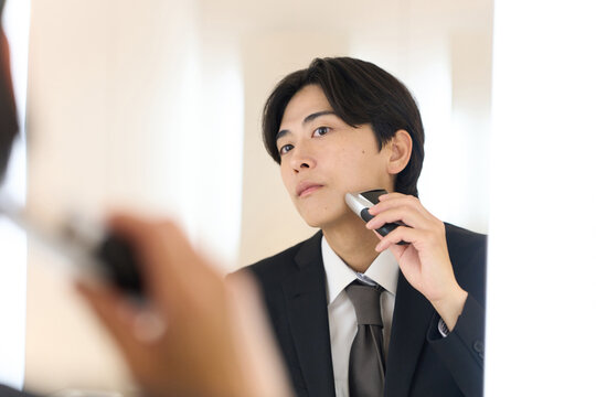身だしなみでヒゲを剃るアジア人ビジネスマン