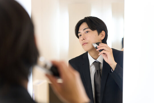 身だしなみでヒゲを剃るアジア人ビジネスマン