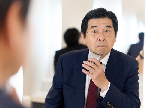 身だしなみでヒゲを剃るアジア人ビジネスマン