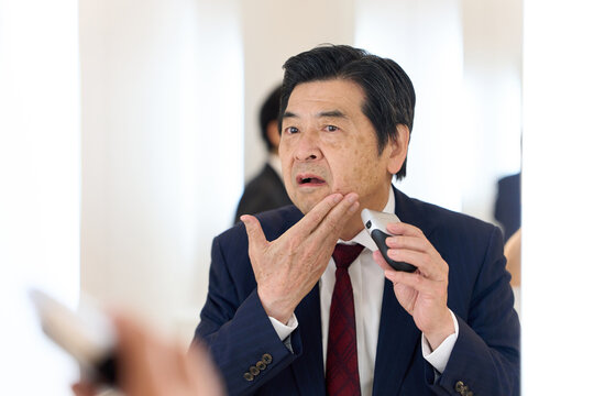 身だしなみでヒゲを剃るアジア人ビジネスマン
