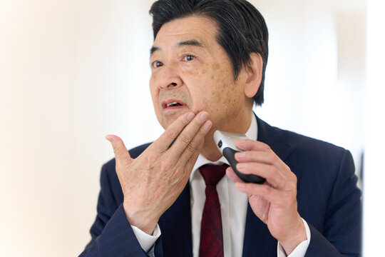 身だしなみでヒゲを剃るアジア人ビジネスマン
