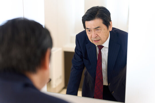 トイレの鏡で表情のチェックをするアジア人男性