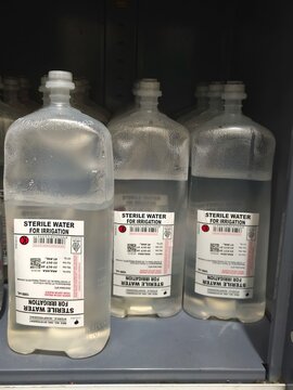 Rows of Sterile Water for Irrigation 1000ml Bottles in a Hospital Medical Storage Cabinet