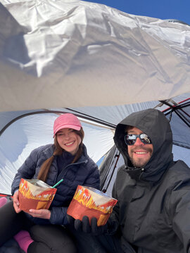 Couple eating camping food inside tent