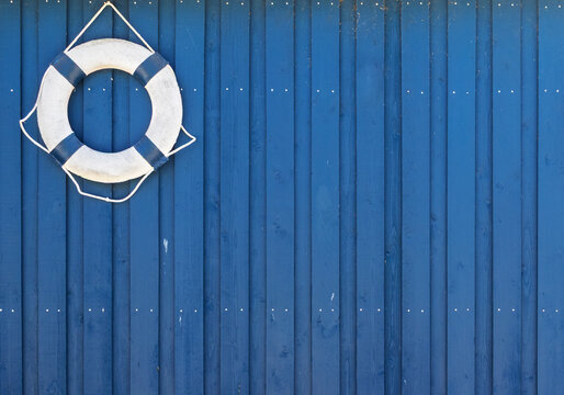 White lifebuoy hanging on blue wooden wall with copy space
